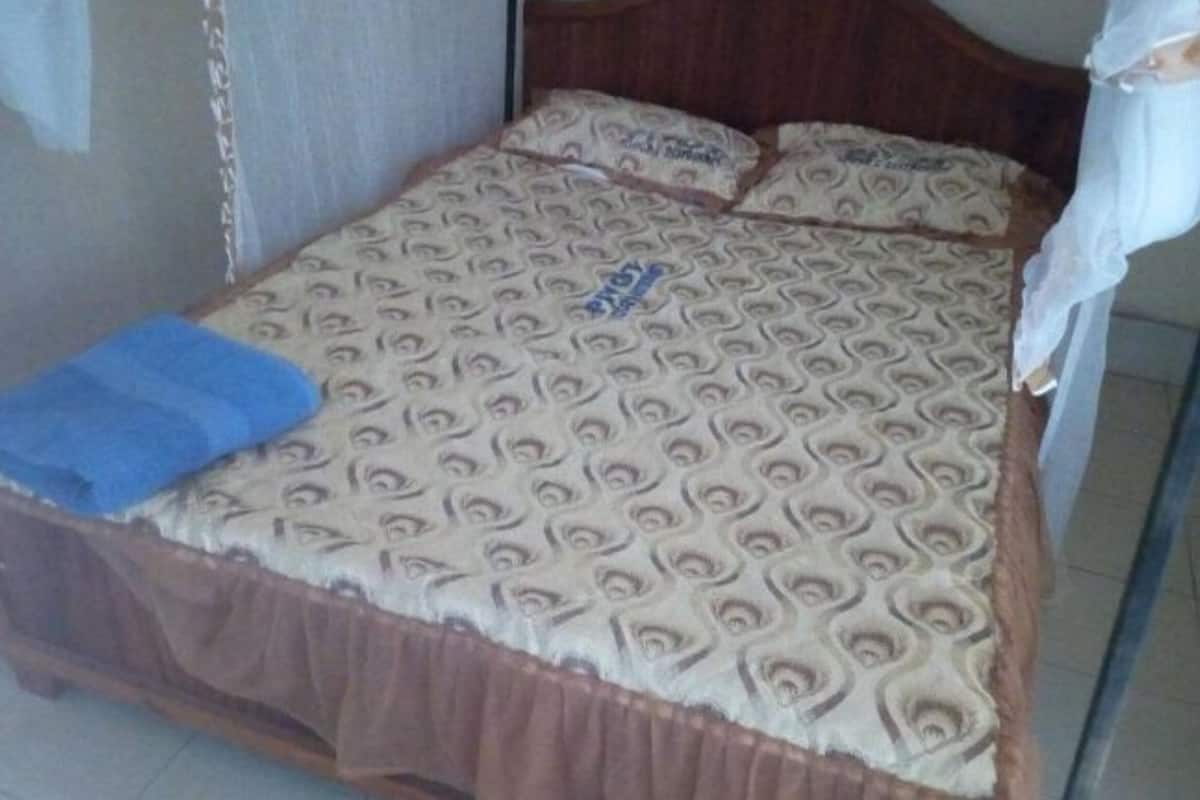 A bed with a patterned bedspread and a blue towel.