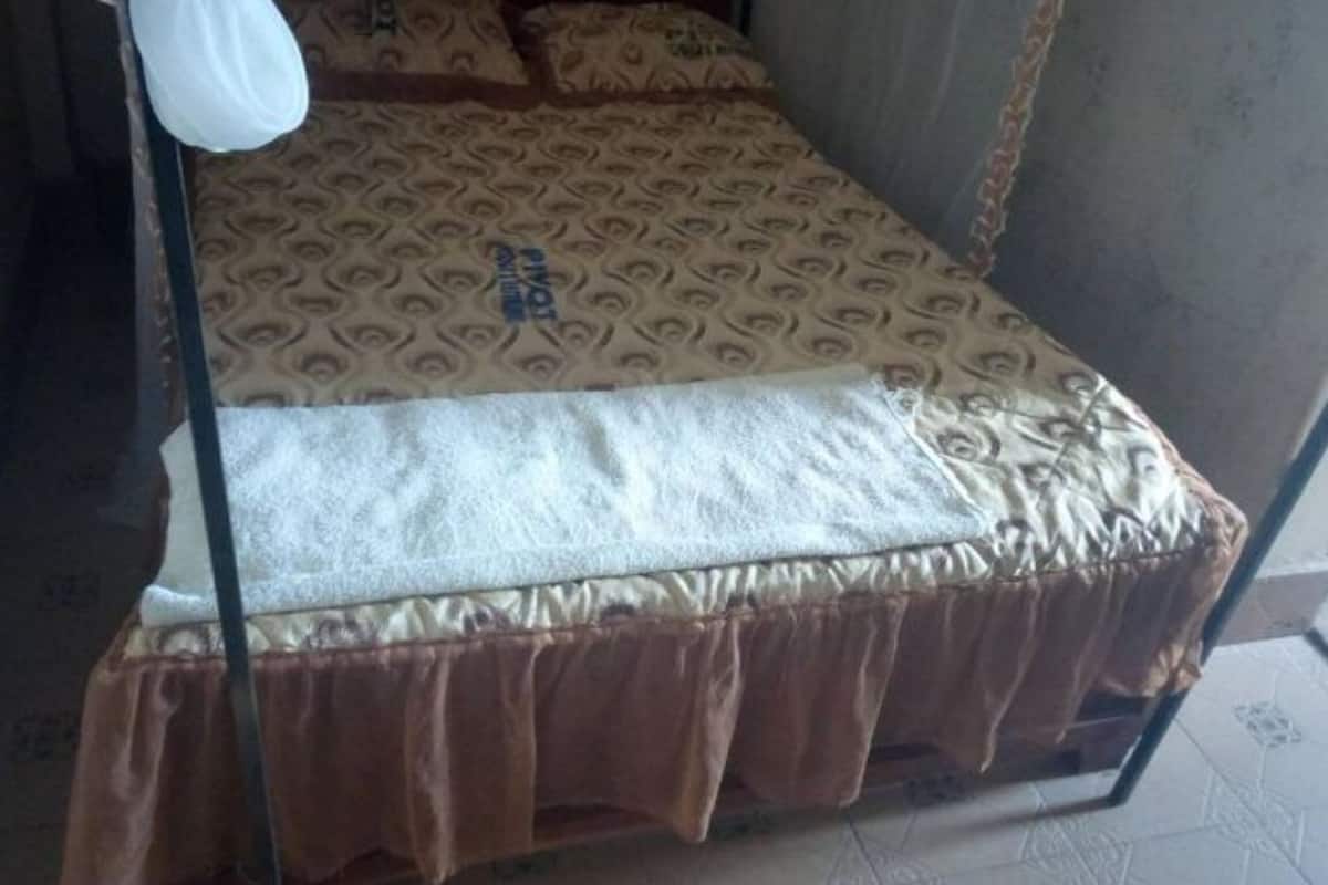 A bed with a patterned bedspread, a white pillow, and a brown skirted frame.