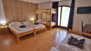 Ein Zimmer mit Etagenbetten, einem Einzelbett, einem Fernseher und Holzboden.