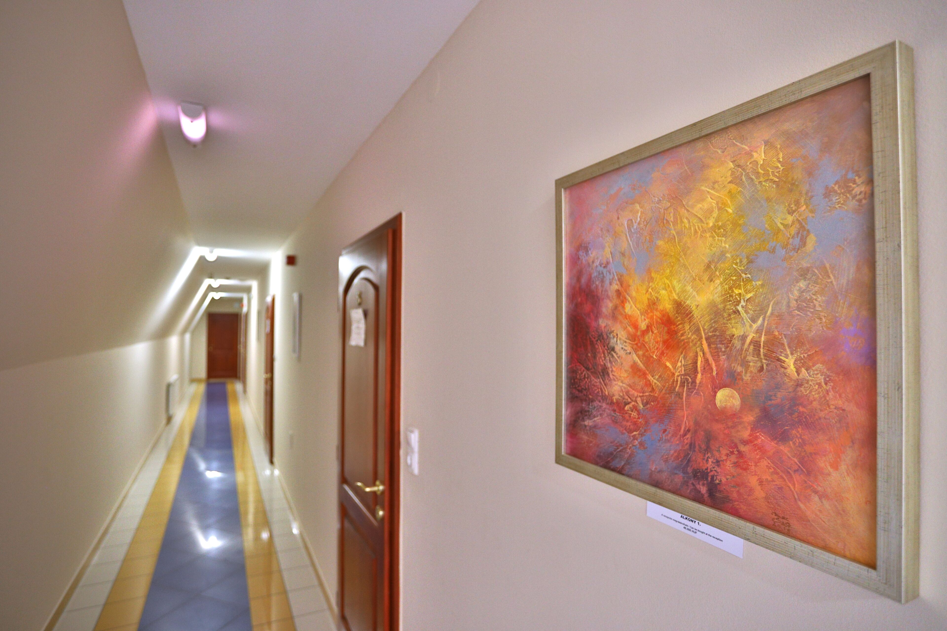A hallway with a blue and yellow striped floor, a painting on the wall, and a door with a wooden frame.