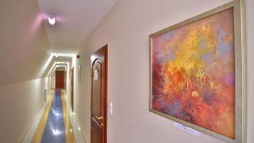 A hallway with a blue and yellow striped floor, a painting on the wall, and a door with a wooden frame.