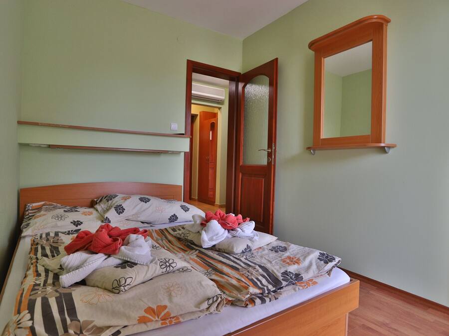 A neatly made bed with floral bedding, a wooden headboard, and a mirror on the wall.