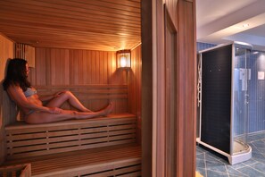 Una sauna con bancos de madera y un ventanal que da a un baño.