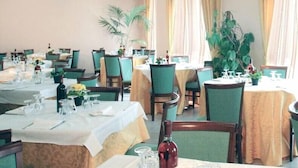 Un restaurante con varias mesas, cada una con mantel blanco, sillas y cristalería.
