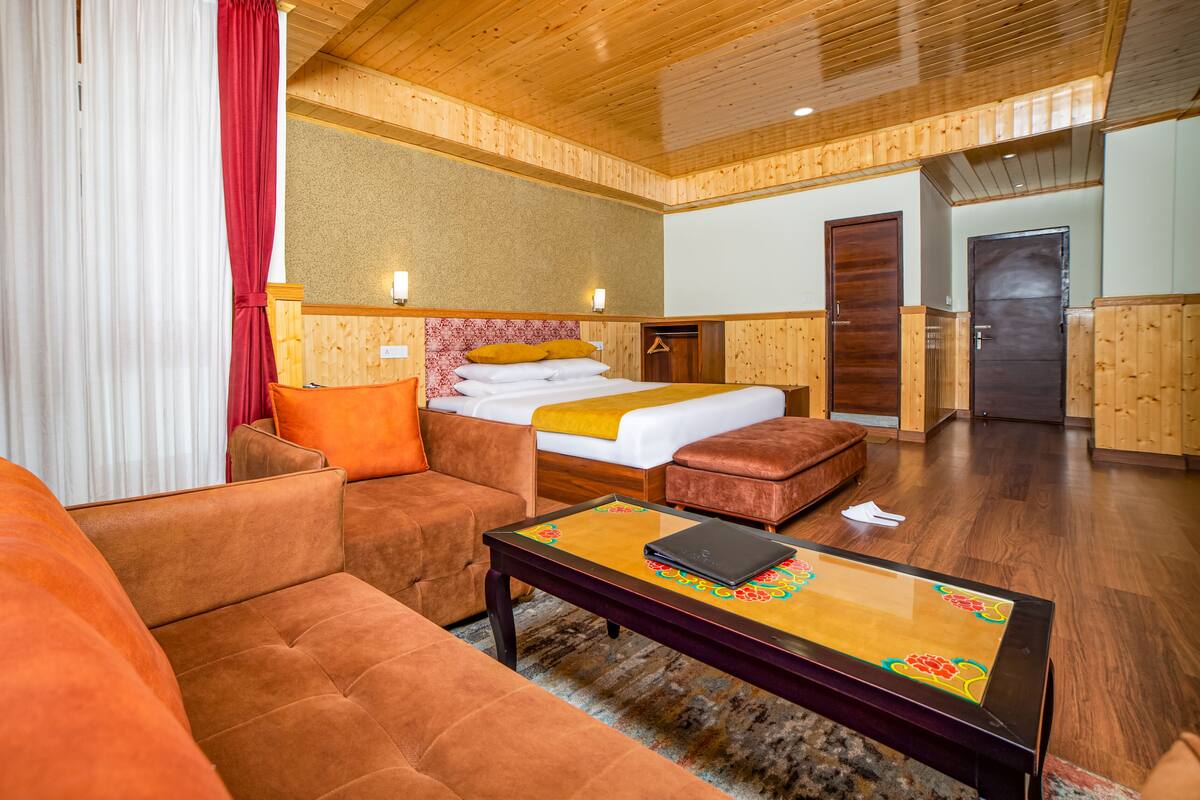 Una habitación de hotel con cama, sofá, mesa de centro y armario.