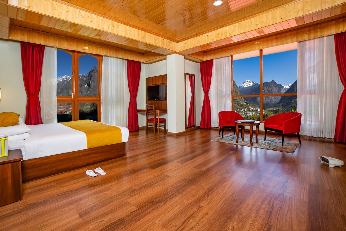 Una habitación de hotel con piso de madera, una cama, un escritorio, una silla y un televisor.