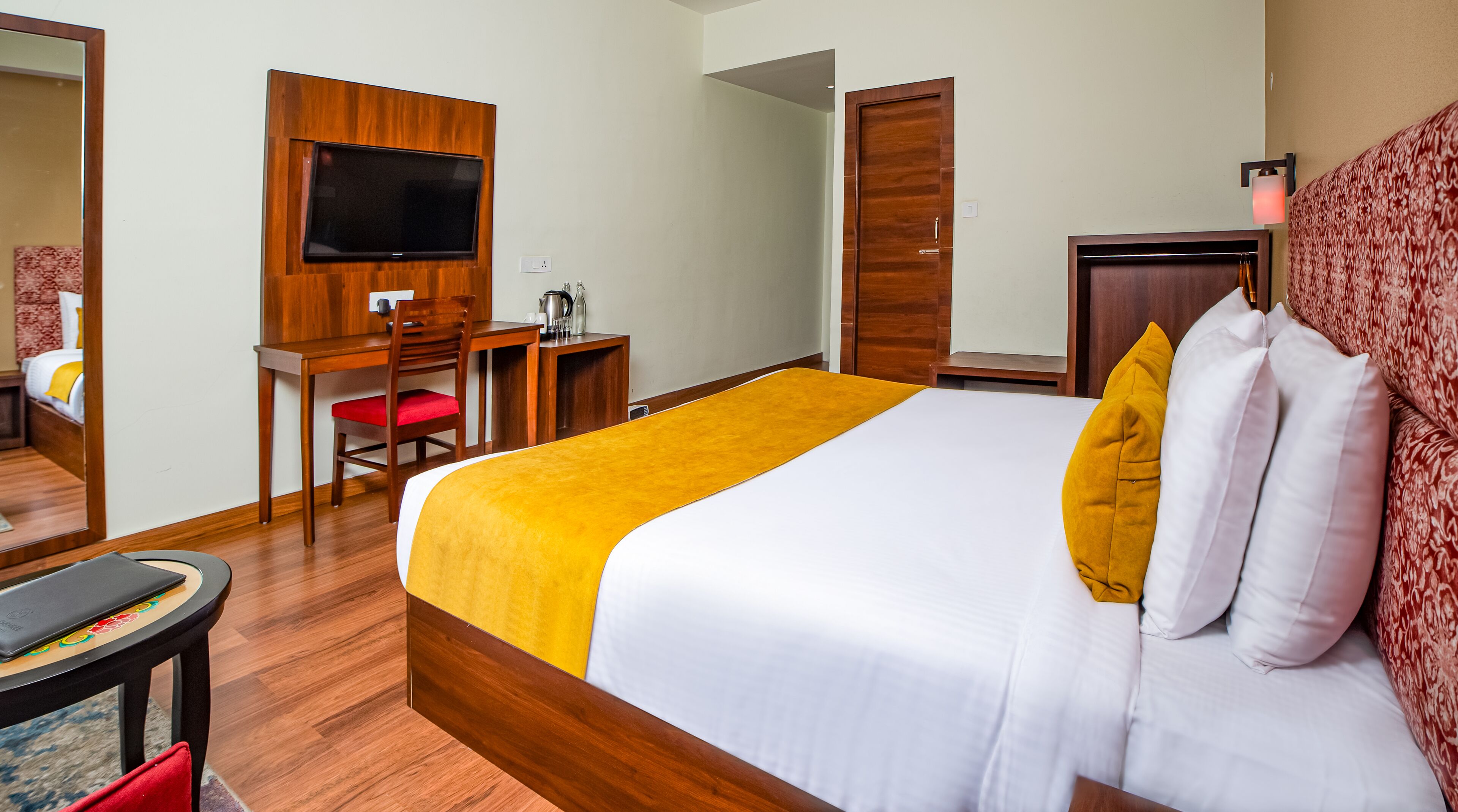 Una habitación de hotel con cama, escritorio, silla, televisor y armario.