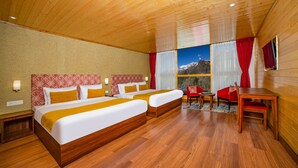 Habitación de hotel con dos camas, techo y suelo de madera, una mesa de comedor y vistas a las montañas.