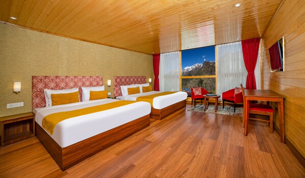 Una camera d'albergo con due letti, soffitto e pavimento in legno, un tavolo da pranzo e vista sulle montagne.