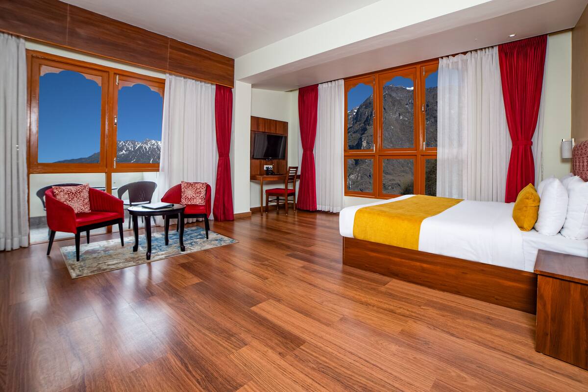 Una habitación de hotel con una cama grande, dos sillones, un escritorio y un televisor.