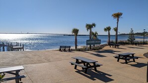 A beachside park with picnic tables, a sign reading "Navarre Beach," and a pier in the background. - Welcome to Beachy Bliss – Your Emerald Waters Escape! (Navarre)