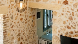 A room with exposed stone walls, a wooden ceiling, and hanging pendant lights.
