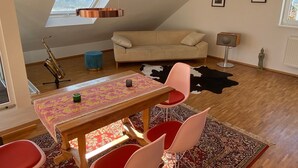A cozy loft apartment with a dining area, a sofa, a small statue, and a cowhide rug.