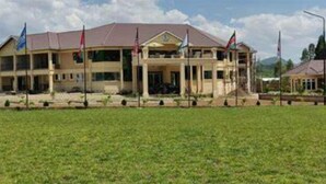 A two-story building with a flat roof and multiple flagpoles. - Koru Country Club (Koru)