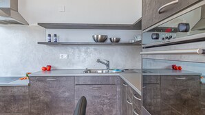 A modern kitchen with grey cabinets, a stainless steel sink, and a built-in oven. - La Luminosa (Bissone)