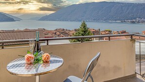 A balcony with a table, two chairs, and a bottle of wine. - La Luminosa (Bissone)