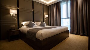 A modern hotel room with a large bed, two bedside tables, and wall-mounted lamps. - Hotel Bay Diab (Algiers)
