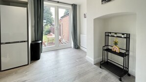 A modern kitchen with a built-in refrigerator, a sliding glass door leading to a patio, and a black metal shelf with decorative items. - Worksop Newly Refurbished 2-bedroom House (Worksop)