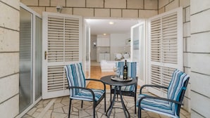 A patio area with two chairs and a table, a bottle of liquor, and a tray. - House Apartments Ariva (Dubrovnik)