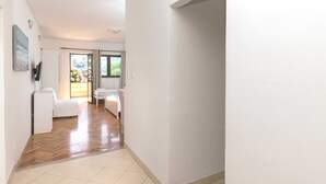 A hallway with a wooden floor, white walls, and a door leading to a balcony with a view of greenery. - House Apartments Ariva (Dubrovnik)