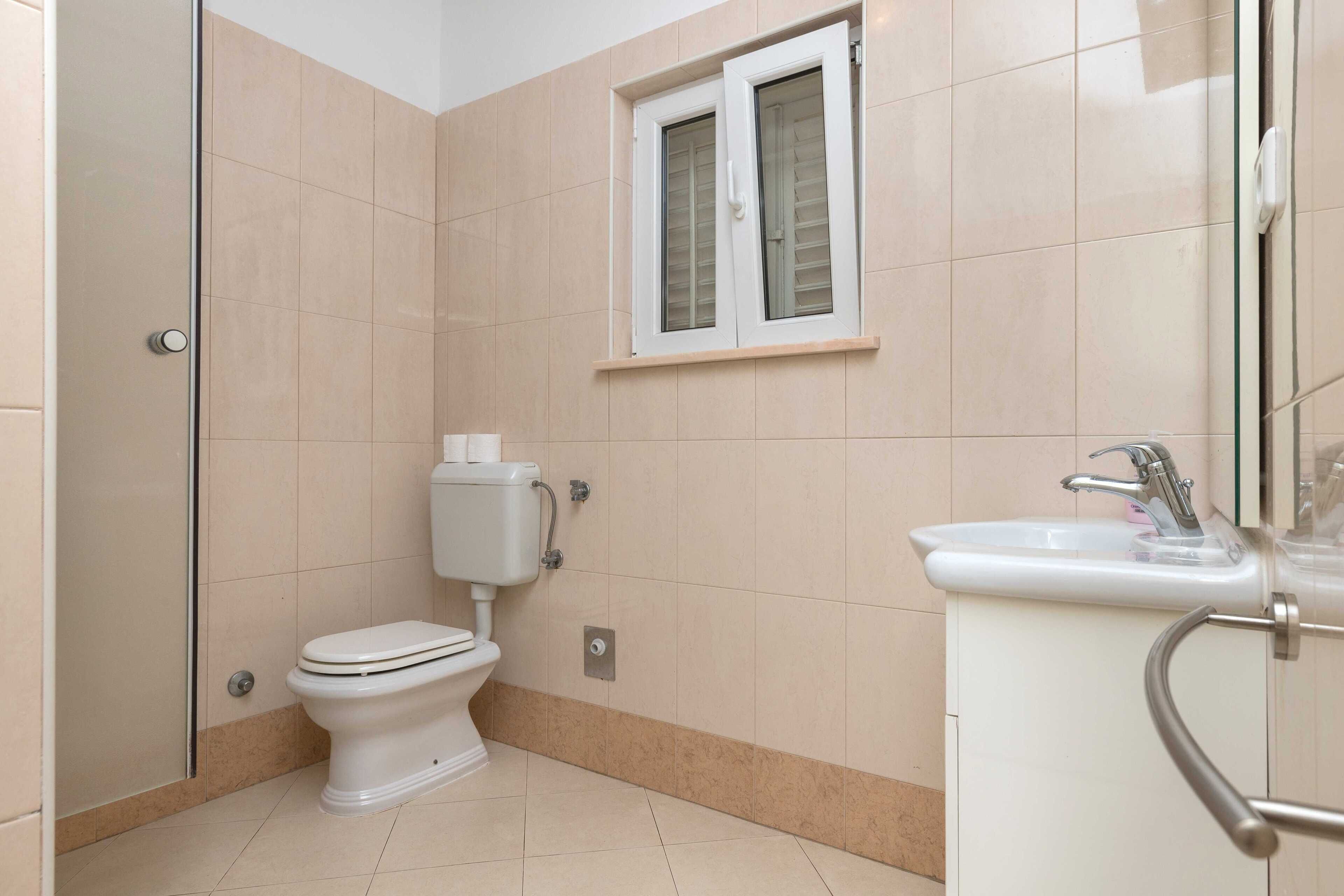 Une salle de bain avec des toilettes, un lavabo et une fenêtre.
