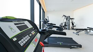 A gym with a treadmill, stationary bikes, and weight machines. - Terminal Inn By Edar City Center (Doha)