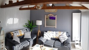 Ein Wohnzimmer mit zwei Sofas, einem Couchtisch, einer Lampe und einem Holzbalken an der Decke.