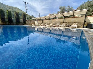 Una piscina al aire libre de temporada, sillones reclinables de piscina