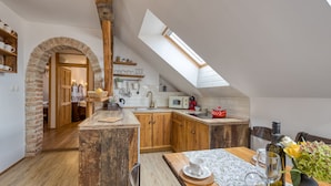 A kitchen with wooden cabinets, a skylight, and a dining area with a table set for two.