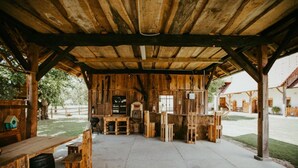 A rustic wooden cabin with a covered patio area, wooden furniture, and a view of the surrounding landscape.