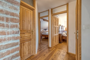 A wooden interior with a brick wall, wooden doors, and a bed in the background. - Family Friendly France's Lair (Ljutomer)