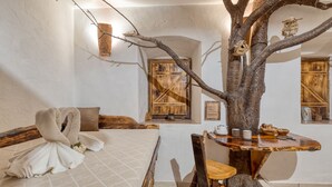 A bedroom with a bed, a wooden table, a chair, and a tree trunk centerpiece.