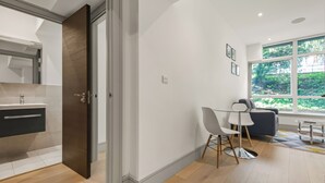 A modern kitchen with a dark wooden door, a white countertop, and a built-in sink. - Charming 1-bed Apartment in Harrow (Harrow)