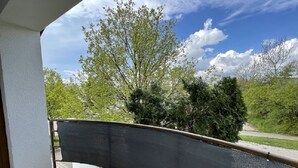 A balcony with a view of a tree-lined street and a clear sky. - 2 Bedroom Apartment in Kempten (Kempten)