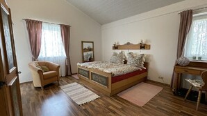 A bedroom with a wooden bed, a chair, a desk, and a window with curtains. - 2 Bedroom Apartment in Kempten (Kempten)