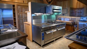 A modern kitchen with stainless steel appliances, wooden cabinetry, and a tiled floor. - Star Ridge | Private Estate | Sleeps 20 | Hot Tub (Wood Township)