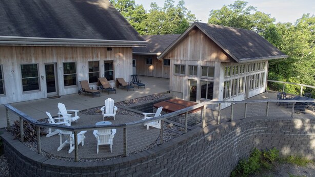 A large house with a covered patio area featuring outdoor seating and a fire pit. - Star Ridge | Private Estate | Sleeps 20 | Hot Tub (Wood Township)
