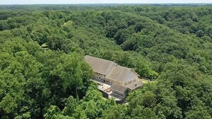 A large, single-story building surrounded by dense forest. - Star Ridge | Private Estate | Sleeps 20 | Hot Tub (Wood Township)