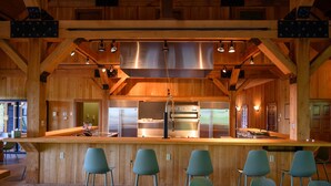 A rustic wooden interior with a central bar area, high ceilings, and modern lighting fixtures. - Star Ridge | Private Estate | Sleeps 20 | Hot Tub (Wood Township)