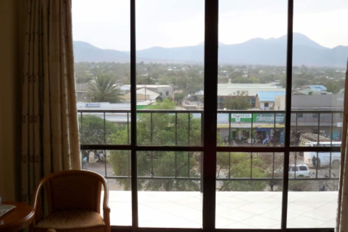 Una habitación con un ventanal amplio que ofrece vistas a un paisaje urbano y montañas.