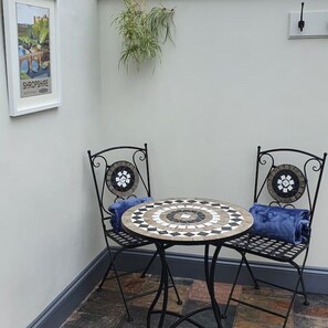 Enjoy a quiet moment on this patio with a round table and two chairs.