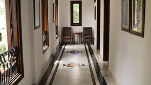 A hallway with a marble floor, framed pictures on the walls, and a wooden bench. - Sun N Snow Inn By Leisure Hotels (Somashwar)