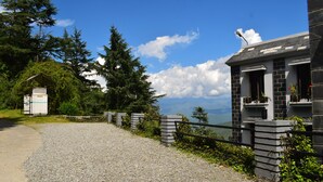 A gravel path leading to a stone building with a balcony, surrounded by greenery and overlooking a scenic view. - Sun N Snow Inn By Leisure Hotels (Somashwar)