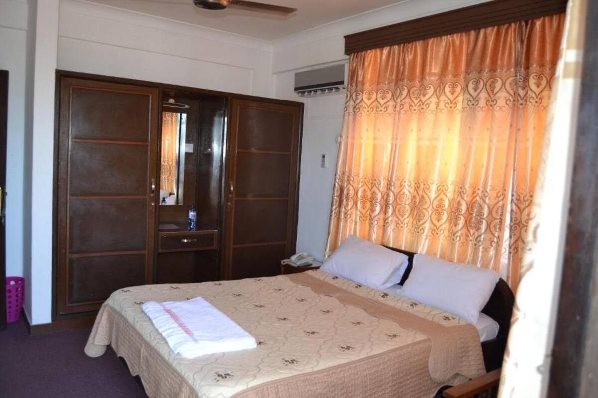 Une chambre à coucher avec un lit, une armoire et un rideau.