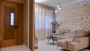 A living room with a stone wall, a beige sofa, a small round table, and a wooden door with a window.