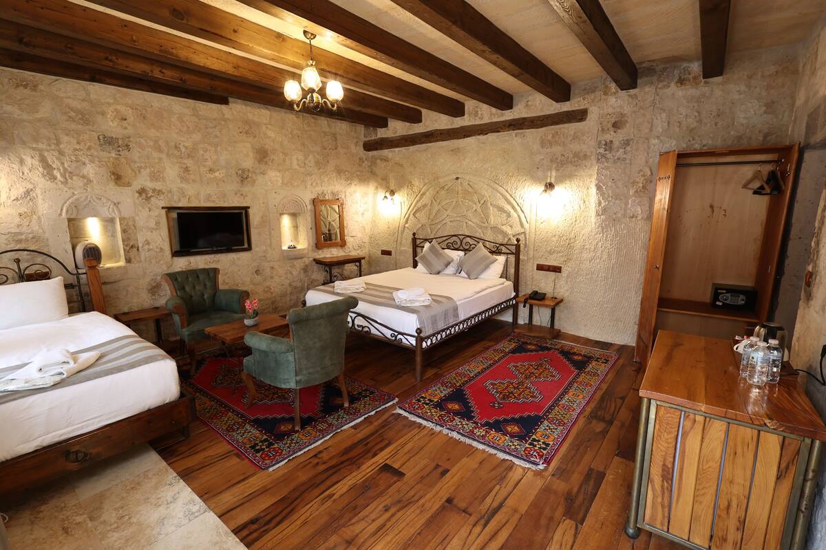 A rustic bedroom with a wooden bed, a green armchair, a small table, and a wooden cabinet.