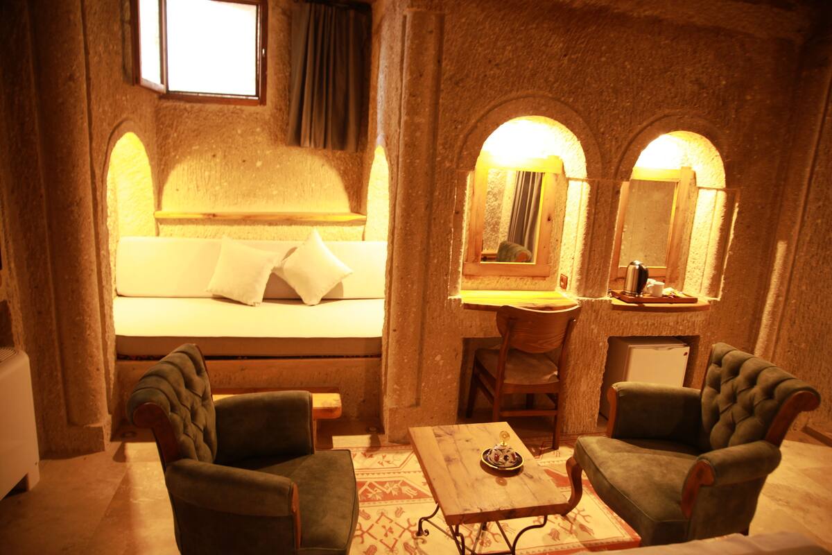 A cozy room with a bed, two armchairs, a small table, and a mirror.