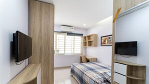Ein Schlafzimmer mit Bett, Schreibtisch, Fernseher und Kleiderschrank.