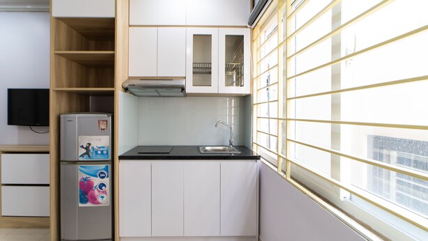 Eine kompakte Küche mit weißen Schränken, einer schwarzen Arbeitsplatte und einem eingebauten Kühlschrank.