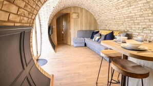 Ein gemütlicher, halboffener Wohnbereich mit gewölbter Ziegeldecke, einer Holzsofa und einem Essbereich mit Tisch für zwei Personen.